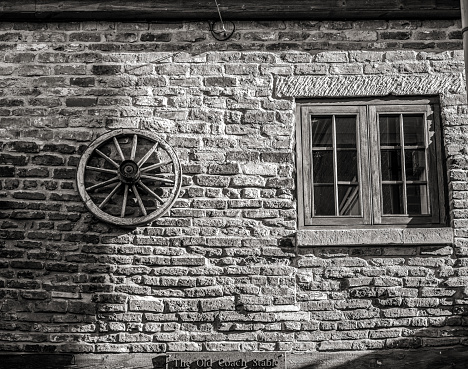 Whitby, UK. February 11, 2020.  An old stable converted to living accommodation.  The old bricks provide texture and a wagon wheel is mounted on the wall next to a window.