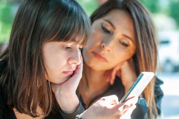istock Cute girl and her mom using mobile phone 1207045277
