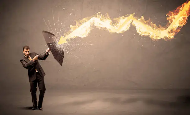 Photo of Business man defending himself from a fire arrow with an umbrella