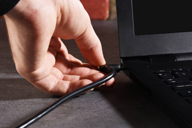 A male hand plugging laptop battery cable