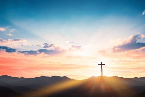 Silhouette cross on mountain sunset background stock photo