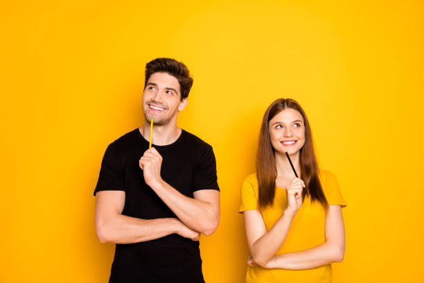 Photo of cheerful positive cute nice charming couple of two people pondering over surprise for each other isolated over vivid color background in black t-shirt Photo of cheerful positive cute nice charming couple of two people, pondering over surprise for each other isolated over vivid color background in black t-shirt two people thinking stock pictures, royalty-free photos & images