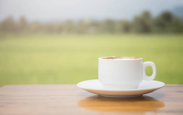 istock A white coffee cup on a wooden table With a backdrop of rice fields. 1207048466