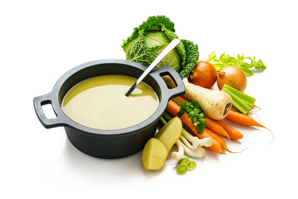 istock Vegetables soup in a cooking pan isolated on white background 1207049502