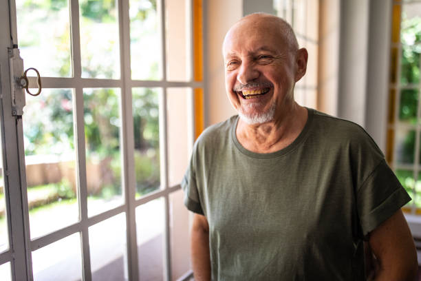 Portrait of happy senior man at home Portrait of casually clothed happy senior man standing near window at home and smilng argentinian ethnicity photos stock pictures, royalty-free photos & images