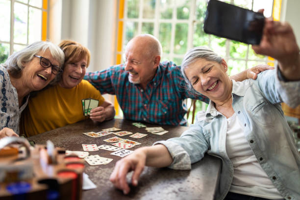 istock Happy senior friends taking selfie while playing cards at home 1207051904