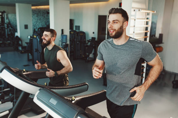 istock Two young man running on treadmill at gym 1207051951