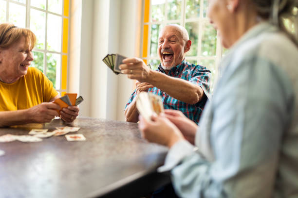 Group of senior friends enjoying while playing cards at home Group of senior friends enjoying while playing cards at home family playing card game stock pictures, royalty-free photos & images