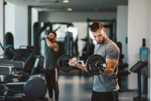 istock Young bearded man doing biceps exercises  in gym with barbell 1207052423