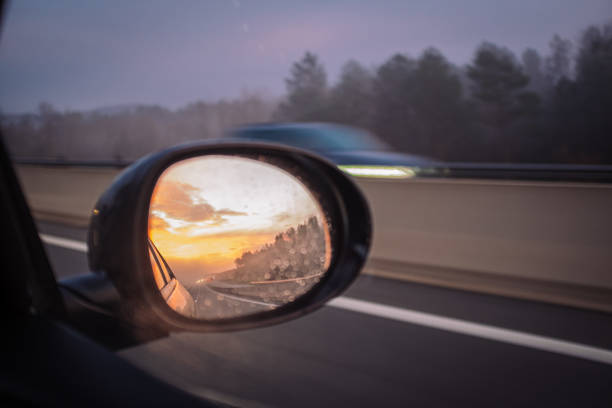 istock Sunrising on an orange cloudscape reflected on a mirror car while driving fast on a highway 1207053960
