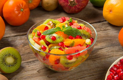 Winter fruit salad in glass salad bowls with fresh ingredients on an old rustic wooden table. Selected focus.