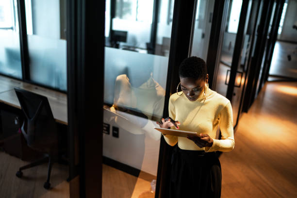 istock Young businesswoman walking and using digital tablet at corridor office 1207053983