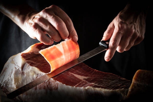 istock Iberian ham serrano ham slice cutting hands and knife 1207055950