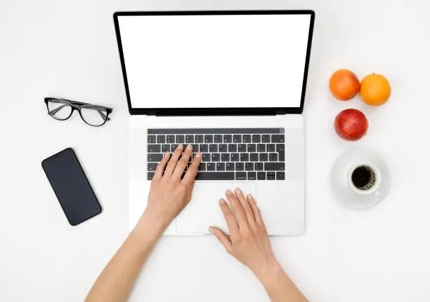 Photo of Top view of beautiful woman 's hands using laptop placed on white desktop. Flat lay