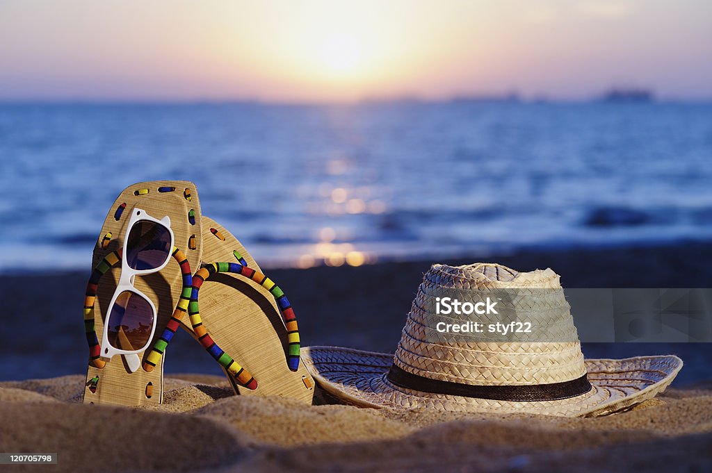 Evening Wicker hat, sandal and glasses on the sandy beach Beach Stock Photo