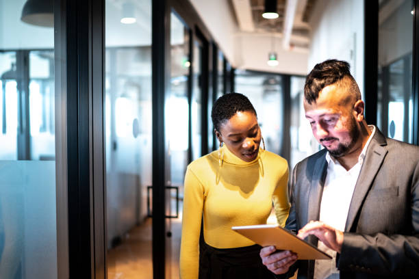 istock Business partners walking using digital tablet at corridor 1207058904