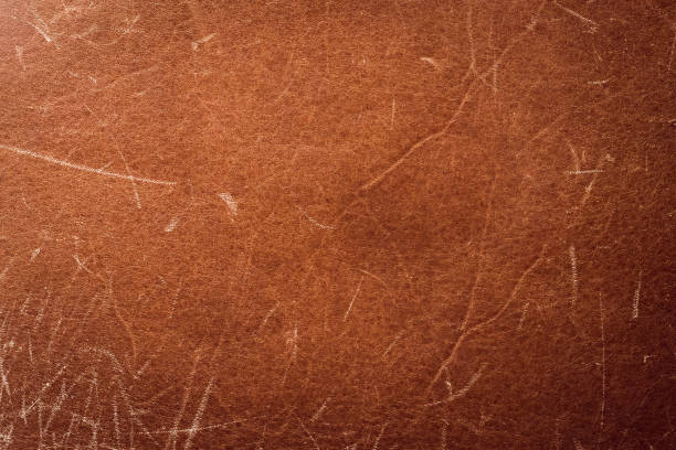 Scratched brown leather texture, background. Worn old skin, abstract pattern. Grunge surface of material, natural vintage belt with scuffs. stock photo