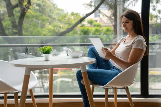 istock Woman at home reading on her tablet while eating a snack 1207059431