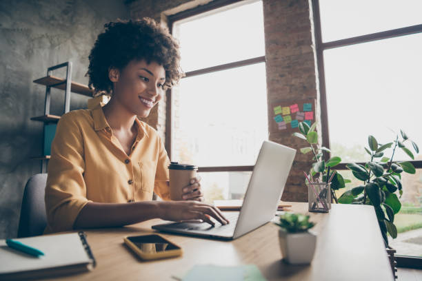 istock Profile side photo of charming smart afro american girl entrepreneur use computer work training company career development seminar sit table hold takeout mug hot beverage in loft office 1207061054