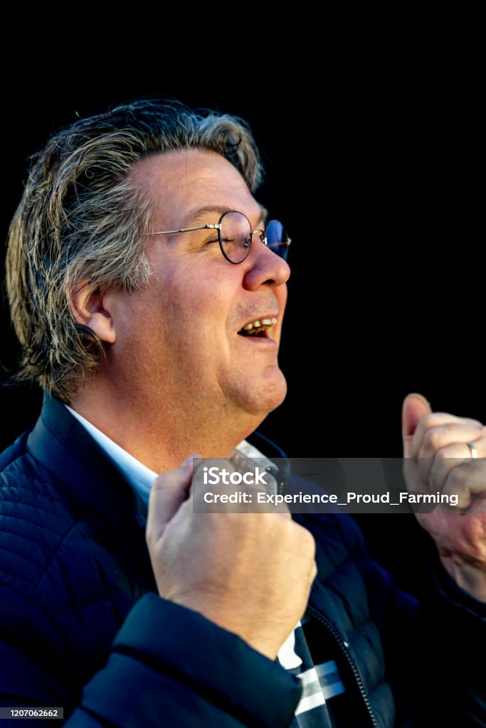 Fortune middle-aged man stands with glasses in front of black background and is very happy Cheerful Stock Photo