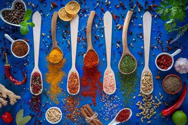 istock Spices herbs condiments on wood spoons at blue background 1207063233