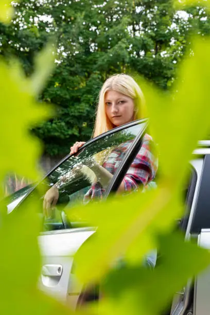 a blonde woman between an open car door in the nature