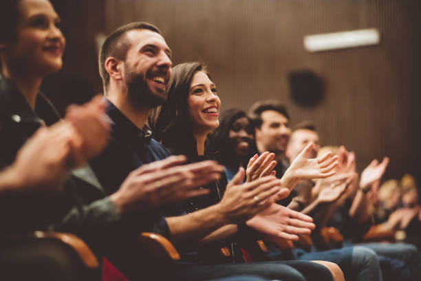 Happy audience applauding in the theater Group of smiling people clapping hands in the theater, close up of hands. Dark tone. Applauding stock pictures, royalty-free photos & images