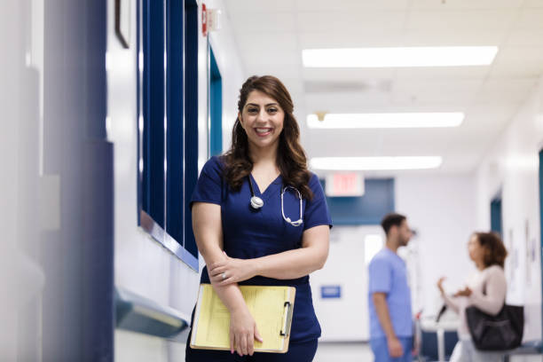 istock Smiling nursing student holding patient chart standing outside patient room 1207069269