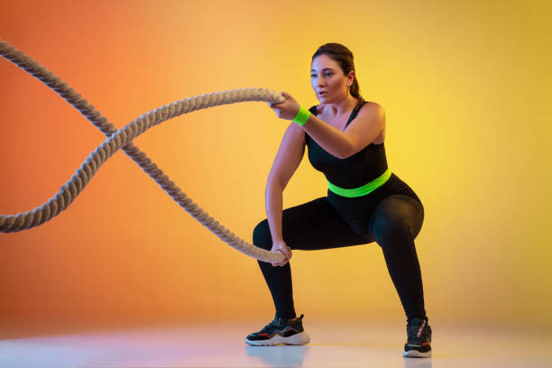 istock Young caucasian plus size female model's training on gradient orange background 1207070765