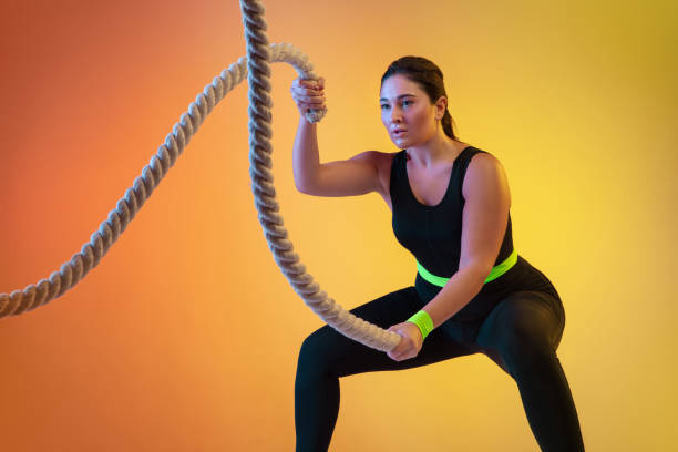 istock Young caucasian plus size female model's training on gradient orange background 1207070770