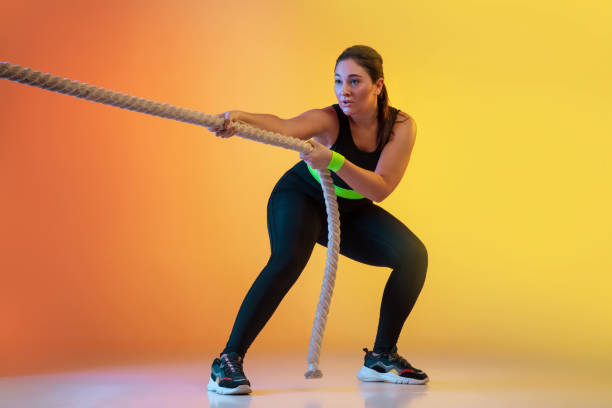 istock Young caucasian plus size female model's training on gradient orange background 1207070774