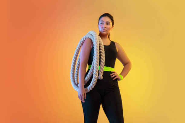 istock Young caucasian plus size female model's training on gradient orange background 1207070784