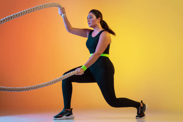istock Young caucasian plus size female model's training on gradient orange background 1207070805