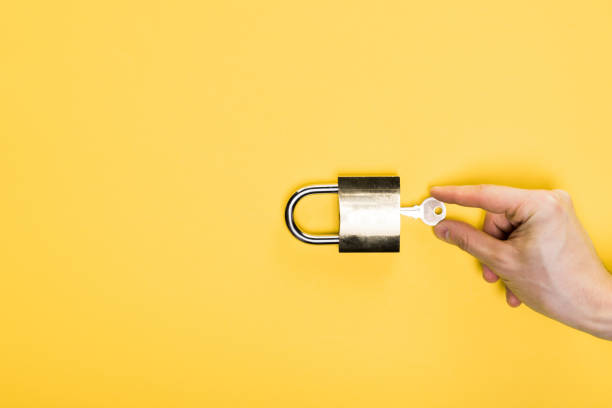 top view of man touching key in metallic padlock isolated on yellow top view of man touching key in metallic padlock isolated on yellow key lock stock pictures, royalty-free photos & images