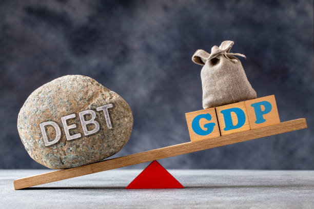 Debt to GDP ratio concept Debt-to-GDP ratio, a large stone with text DEBT and wooden cubes with GDP letters and bag on seesaw giant cube stock pictures, royalty-free photos & images