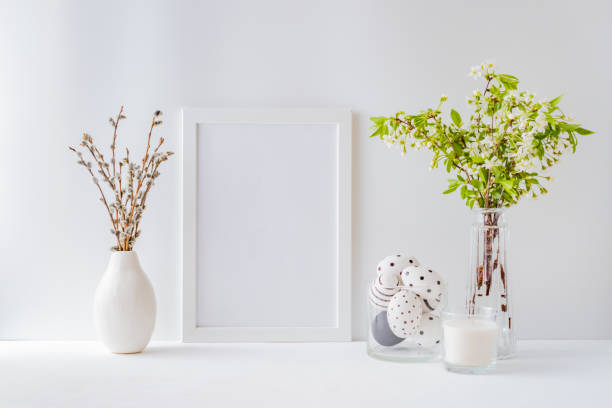 Home interior with easter decor. Mockup with a white frame and spring flowers in a vases on a light background