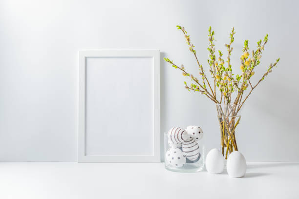 istock Home interior with easter decor. Mockup with a white frame and willow branches in a vase on a light background 1207081474