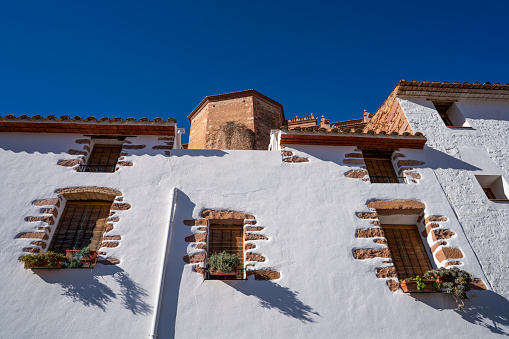 Villafames, Castellon, Spain - January 11, 2020: Villafames also Vilafames village typical traditional architecture of whitewashed facade walls with rodeno red limestone in windows frame in a sunny day, the village is located in Castellon province at Plana Alta of Spain.