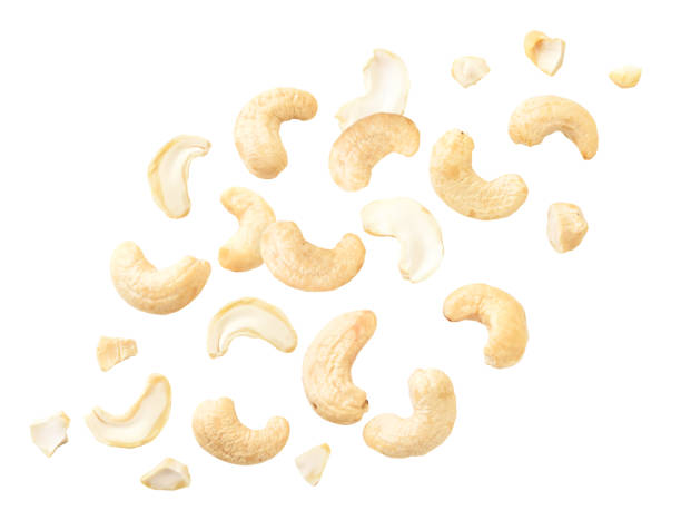 nahaufnahme von cashewkernen, die auf einem weißen fliegen. isoliert - cashewnuss stock-fotos und bilder