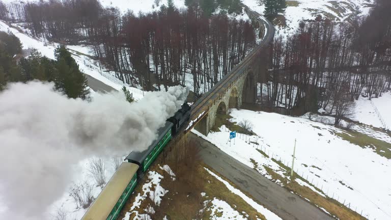 Old steam train crosses snowy landscape. 4K