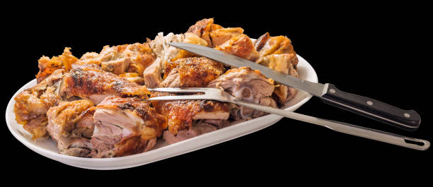 freshly spit roasted pork thigh meat slices offered with serving fork and carving knife on white ceramic tray isolated on black background - roasted spit roasted roast pork barbecue grill imagens e fotografias de stock