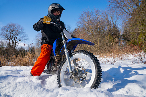 Teen riding a dirt bike in the winter.