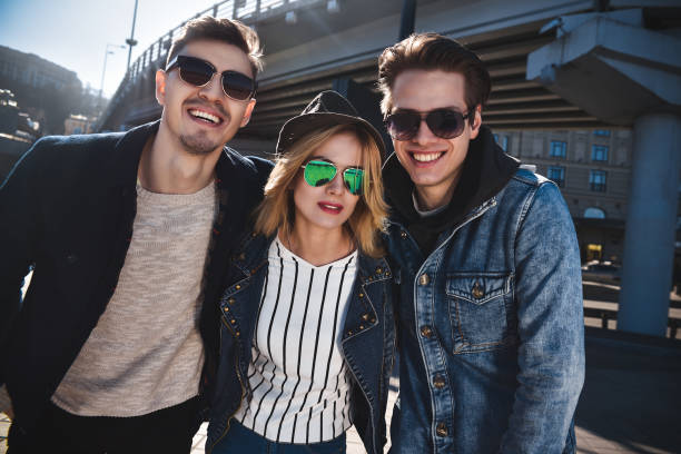 A group of three friends having fun and laughing at street. They are so funny. Group of smiling friends having fun enjoying themselves outdoors. three way kiss stock pictures, royalty-free photos & images