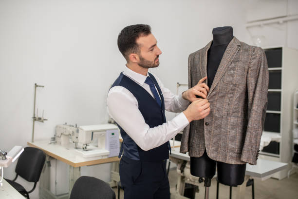 Male fashion designer buttoning up grey jacket