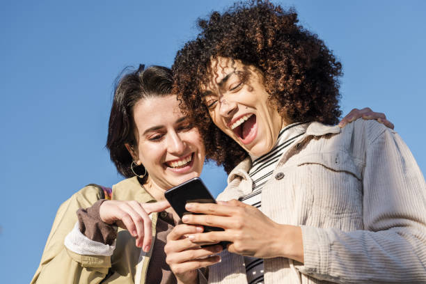 istock two young women laughing watching the phone 1207089322