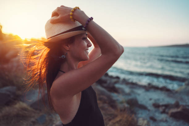 mujer feliz en la costa disfrutando de la puesta de sol - beach sea zen like nature fotografías e imágenes de stock