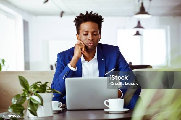 Bored Male Financial Advisor Looking At Laptop Stock Photo - Download Image Now - Boredom, African-American Ethnicity, Financial Advisor