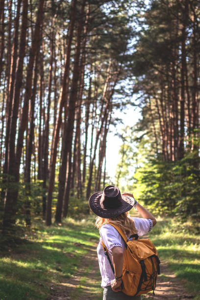 istock Woman with hat and backpack hiking in forest 1207091129