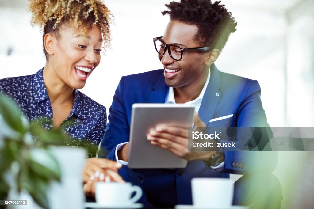 Businessman showing digital tablet to colleague Businessman showing digital tablet to cheerful female colleague. Corporate executives are working related finance. They are in office. 30-34 Years Stock Photo