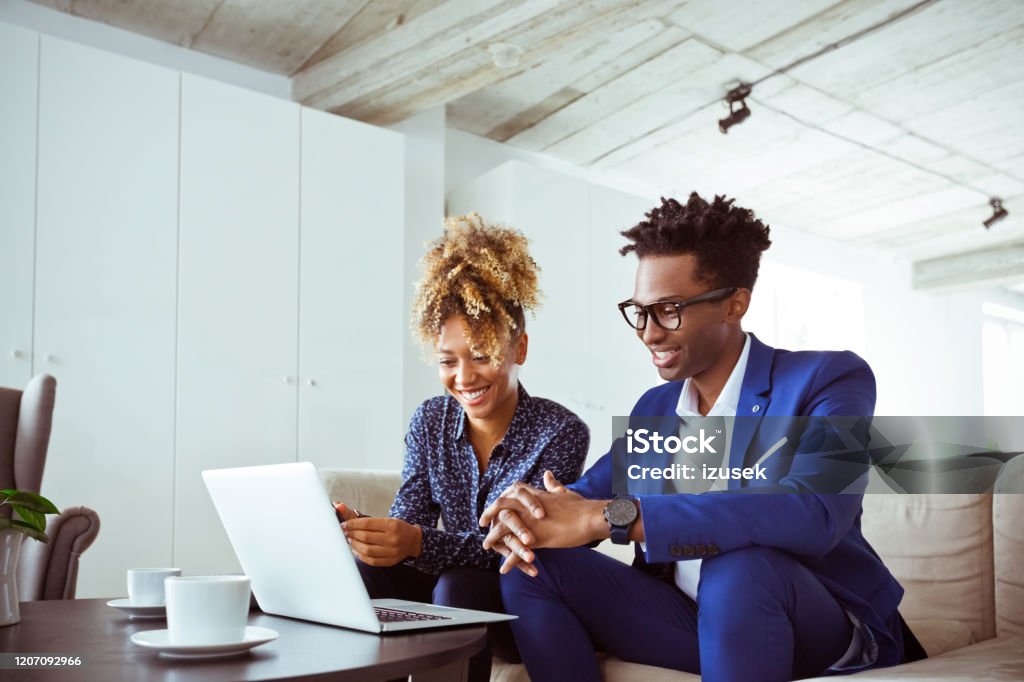 Confident business colleagues looking at laptop Confident smiling business colleagues looking at laptop. Financial professionals are working together in office. They are wearing formals. Working Stock Photo